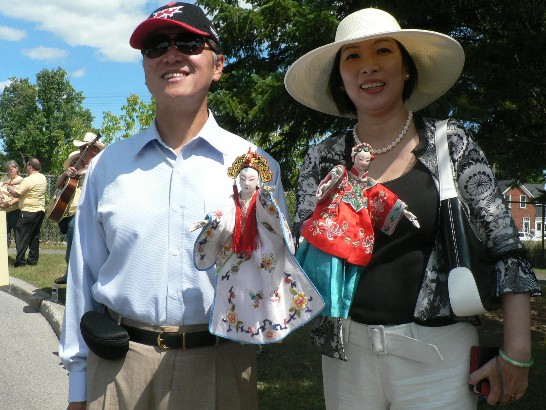 駐加拿大代表李大維伉儷參加加拿大國際偶戲節 (Puppets Up! Festival) 遊行活動，手持台灣布袋戲與參觀遊行民眾親切互動