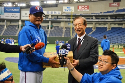 ３月８日に東京ドームで開幕するワールド・ベースボール・クラシック（ＷＢＣ）第２ラウンド１組に出場する台湾代表チームが、試合に先立ち３月７日正午から１時間半にわたり、東京ドームで公式練習を行った。これに合わせて、台湾代表チームの出場選手を激励するため、台北駐日経済文化代表処の羅坤燦・駐日副代表（写真右）が公務出張中の沈斯淳・駐日代表の代理として同日正午に東京ドームを訪れ、試合に向けて練習に励む選手らにリンゴとミネラルウォーターを贈り、謝長亨監督（左）に手渡した。