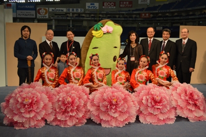 第２４回「世界らん展日本大賞２０１４」が２月１５日に東京ドームで開幕した。同展は２月１５日から２月２３日まで一般公開される。同展開会式が行われた１５日は、台北駐日経済文化代表処の沈斯淳・代表（後列右３）が会場に駆けつけ、台湾の出展業者のブースを一つ一つ回って激励した。メインステージでは、台湾の小中学生で構成される「水精霊児童舞団」（前列）によるパフォーマンスが披露された。また、ステージでは、台湾の形をした「ゆるキャラ」の「タイワンダー☆」（中央）が応援に駆けつけ、エバラ健太さん（後列左１）が歌うテーマソング「南の島のタイワンダー☆」に合わせてダンスも披露し、会場を盛り上げた。