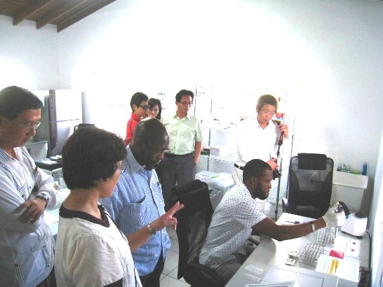 克方合作人員Javeim Blanchette（右方就坐者）實地操作RBPR農藥殘毒檢測，行政院農委會周桃美副研究員(左二)向道總理(左三) 及曹大使(左一)解說相關細節