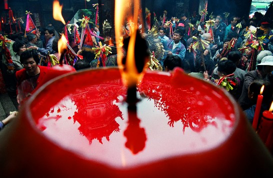 嘉義縣新港奉天宮廟會，大批信徒膜拜祈福，與大紅蠟燭燭油中的倒影相映成趣。（孫寶岳  拍攝）