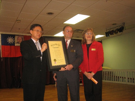 曾瑞利處長(右)接受多拉維爾市市長Ray Jenkins(中)及市議員Pam Fleming贈交之「中華民國日」賀狀。