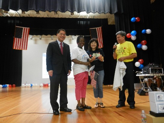 聯邦眾議員Sheila Jackson Lee(D-TX)捐贈100美元予愛心組織，並與廖處長、該組織會長高嫚璘及前會長黃登陸在台上合影留念