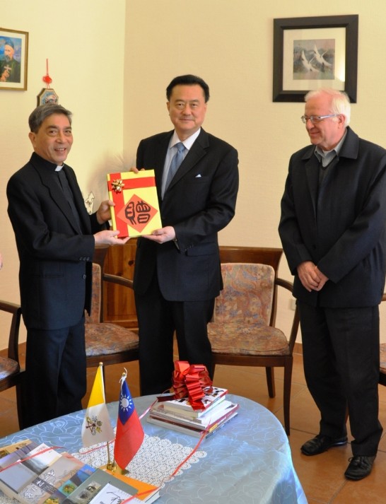 Ambassador Wang (middle) holds a book together with Fr. Pernia while Fr. Kehler stands close to them