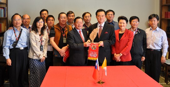 Commissioner Liu and Ambassador Wang exchange gifts surrounded by the members of the delegation.