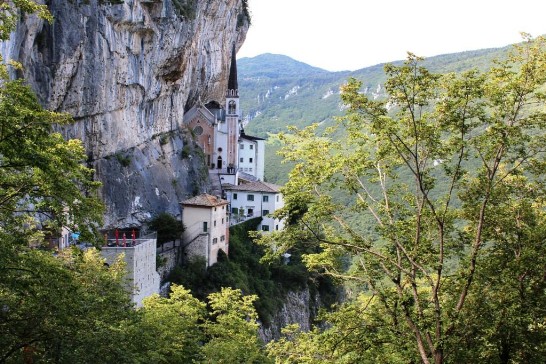 The charming Sanctuary of Our Lady of the Crown clinging to the rocky wall of Mount Baldo