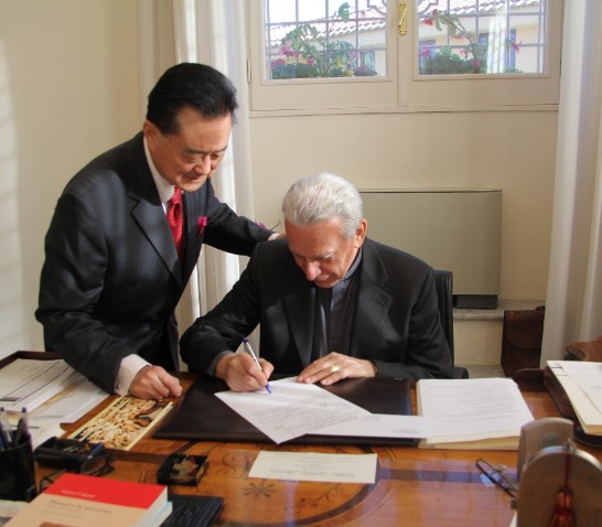 Rector Alberto Trevisiol (right) signs the donation receipt to be given to Ambassador Larry Wang (left).
