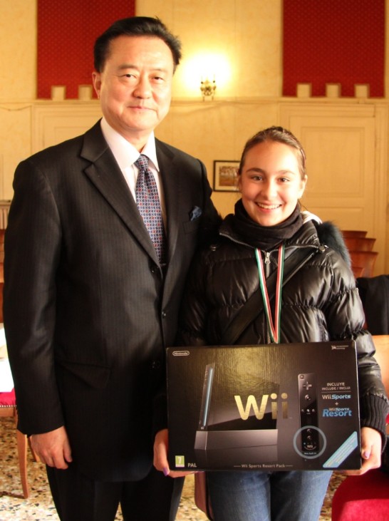 Ambassador Wang (1st from left) with the female child winner of the drawing contest who proudly shows the prize given to her by Ambassador Wang