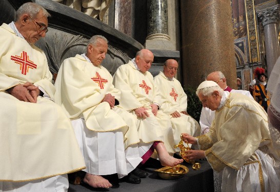 The Holy Father pours water from a gold pitcher over the priest’s feet before washing them