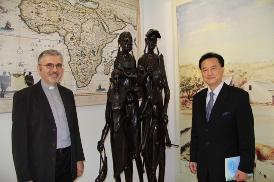 Ambassador Larry Wang (1st from right) and Fr. Marek Rostkowski (1st from left) pose in front of two African warriors and a map of Africa inside the Urbaniana Library.