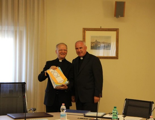 Msgr. Vincenzo Zani (left) shows a gift received by Fr. Leszek Niewdana (right). 