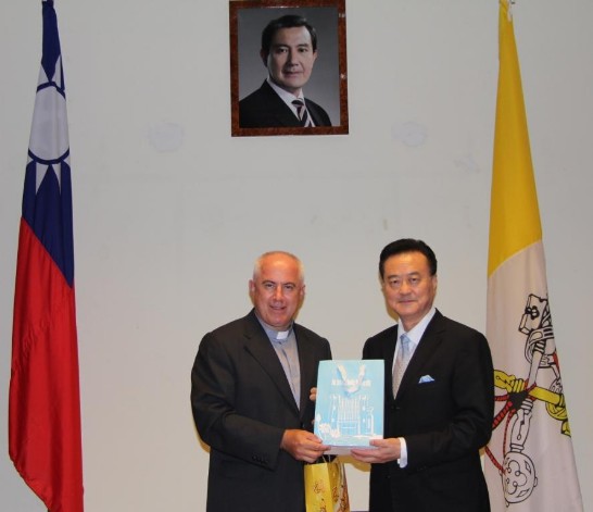Ambassador Larry Wang (right) holds a gift just presented to him by Fr. Leszek Niewdana (left).