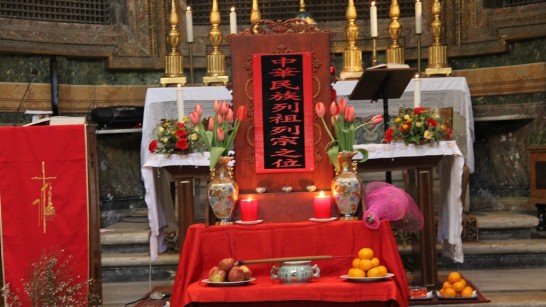 A view of the ancestral table set up in front of the altar full of gifts: fruit, wine, and flowers.