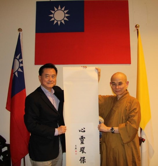 Ambassador Larry Yu-yuan Wang holds a banner showing the calligraphy work by the founder of the Dharma Drum Mountain (Bhikshu Sheng Yen) donated by Venerable Hui-min Shi.