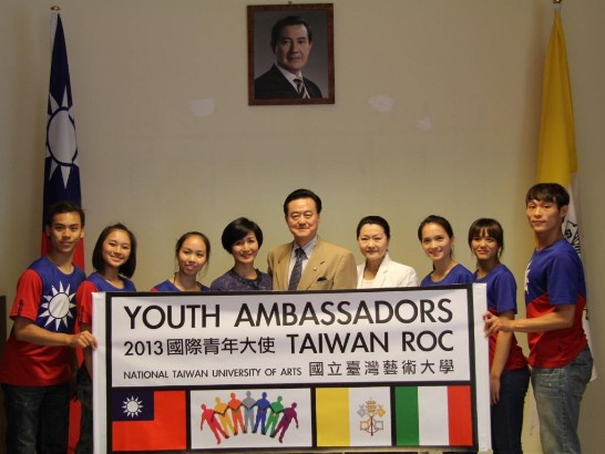Ambassador and Mrs. Larry Wang (5th and 4th from right), Prof. Zhao-Shun Zeng (4th from left) and the Youth Ambassadors in front of President Ma’s portrait and amidst  the ROC and Vatican flags. 