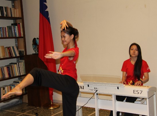 A dancer performs in front of Ambassador Larry Wang and the Embassy staff while another member plays the piano