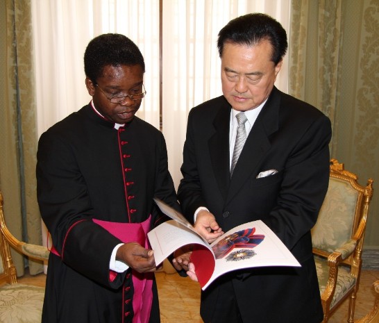 教廷國務院禮賓司司長Msgr. Fortunatus Nwachukwu蒙席（左）向中華民國駐教廷大使王豫元（右）解釋「庇護九世大十字騎士大綬勳章」說明書內容