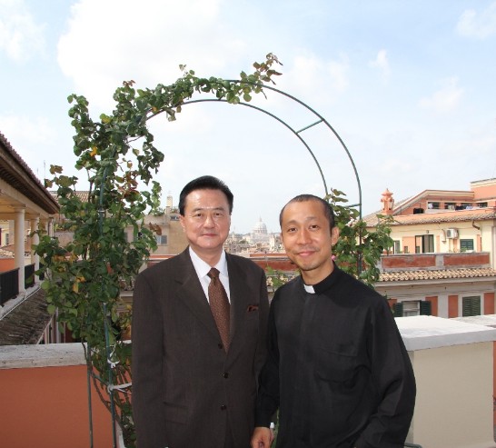 王大使豫元（左）與天主教耶穌會San Roberto Bellarmino修院Guevara神父（右）在該修院頂樓陽台合影（兩人中間背景為梵蒂岡聖伯多祿大教堂）。