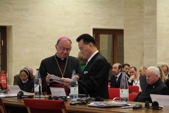 醫牧會主席齊懋斯基總主教（左一）與本館王豫元大使交談並翻閱大會議程