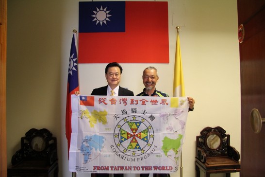 駐教廷大使王豫元（左）與環球騎士陳敏先（右）在大使館共持印有中華民國及教廷國旗之環球行程圖合影