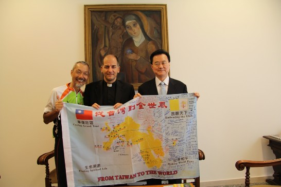 駐教廷大使王豫元（右）與教廷「一心委員會」秘書長Giovanni Dal Toso蒙席（中）、環球騎士陳敏先（左）在「一心委員會」會客室共持印有中華民國及教廷國旗之環球行程圖合影