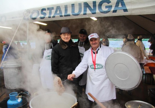 王大使（左）與蒙特福地慈善活動贊助商Avesani（右）在熱食區合影，大鍋內正烹煮當地特色菜（牛舌）