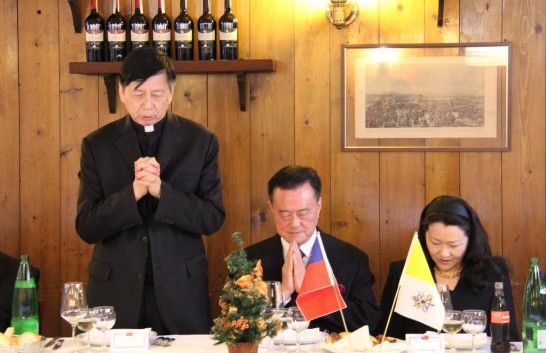 教廷萬民福音部秘書長韓大輝總主教（站立者）帶領餐前祈禱，王大使夫婦（右）一同頌念祈禱文
