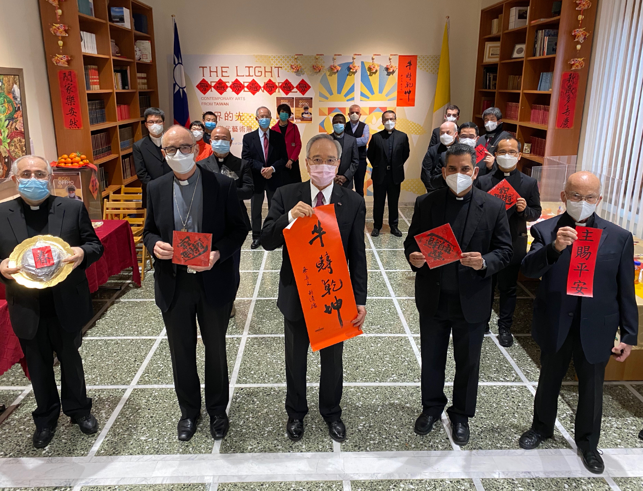 駐教廷大使李世明（中）手持總統蔡英文牛轉乾坤春聯，與教廷樞機主教錢尼（左2）等神職人員歡慶農曆春節。
