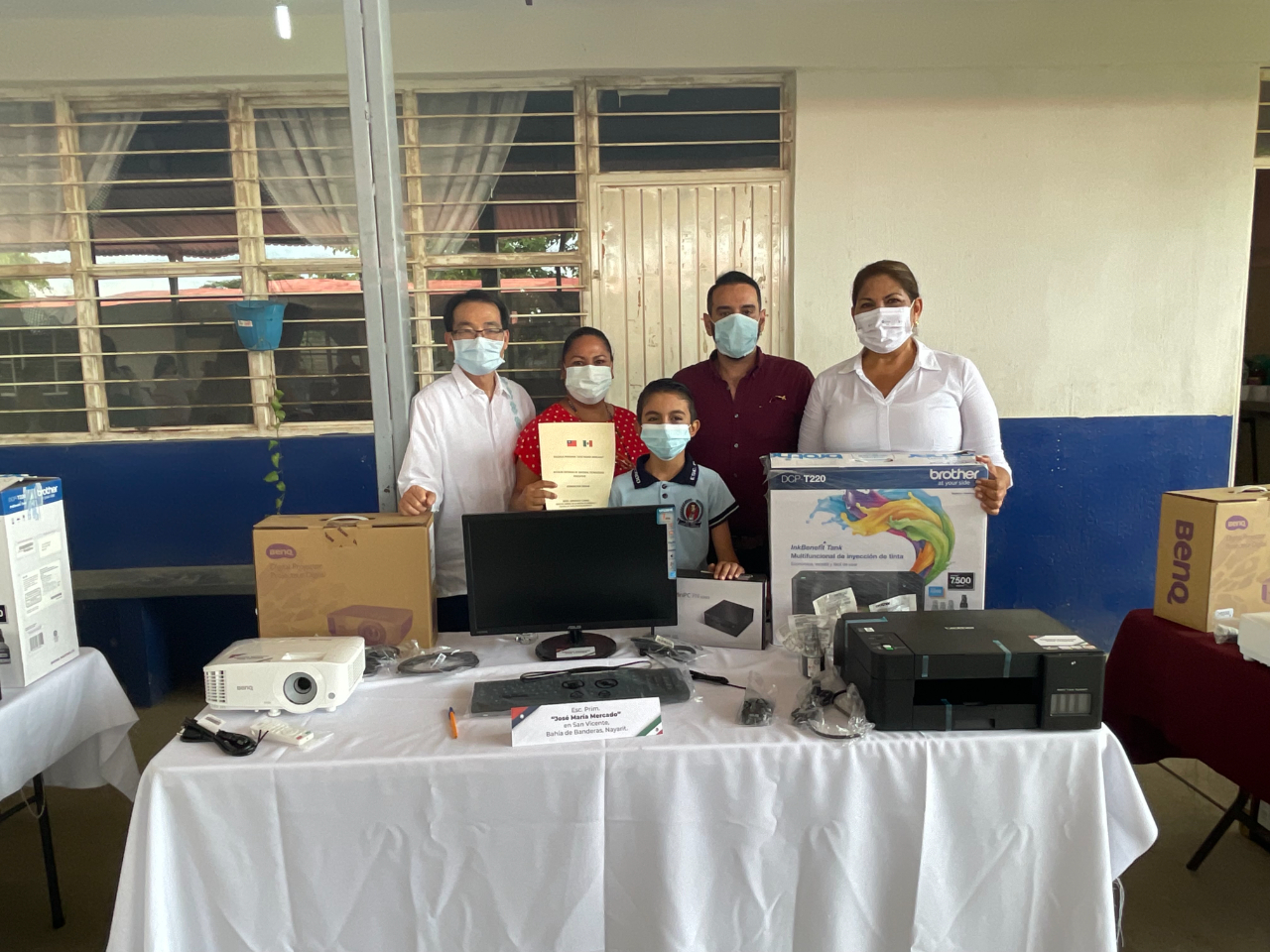 鄭代表、納亞力州教育廳初等教育處長李維拉（右2）、聯邦眾議員蕾佳拉朵（右1）、受贈學校「荷西馬莉亞梅卡多（José María Mercado）小學」代表（左2）及該校獲頒「納亞力州優秀學童」艾南德茲（Kaleb Emiliano Hernández Michel）（中）與我捐贈資訊設備乙批合影。