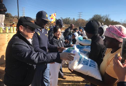 本處賀副代表忠義(左1)、南非警察局Tommy Mthombeni將軍(左2)及慈濟基金會南非分會鄭副執行長愛寶(左3)發放Mooiplaas貧戶來自台灣的愛心白米 
