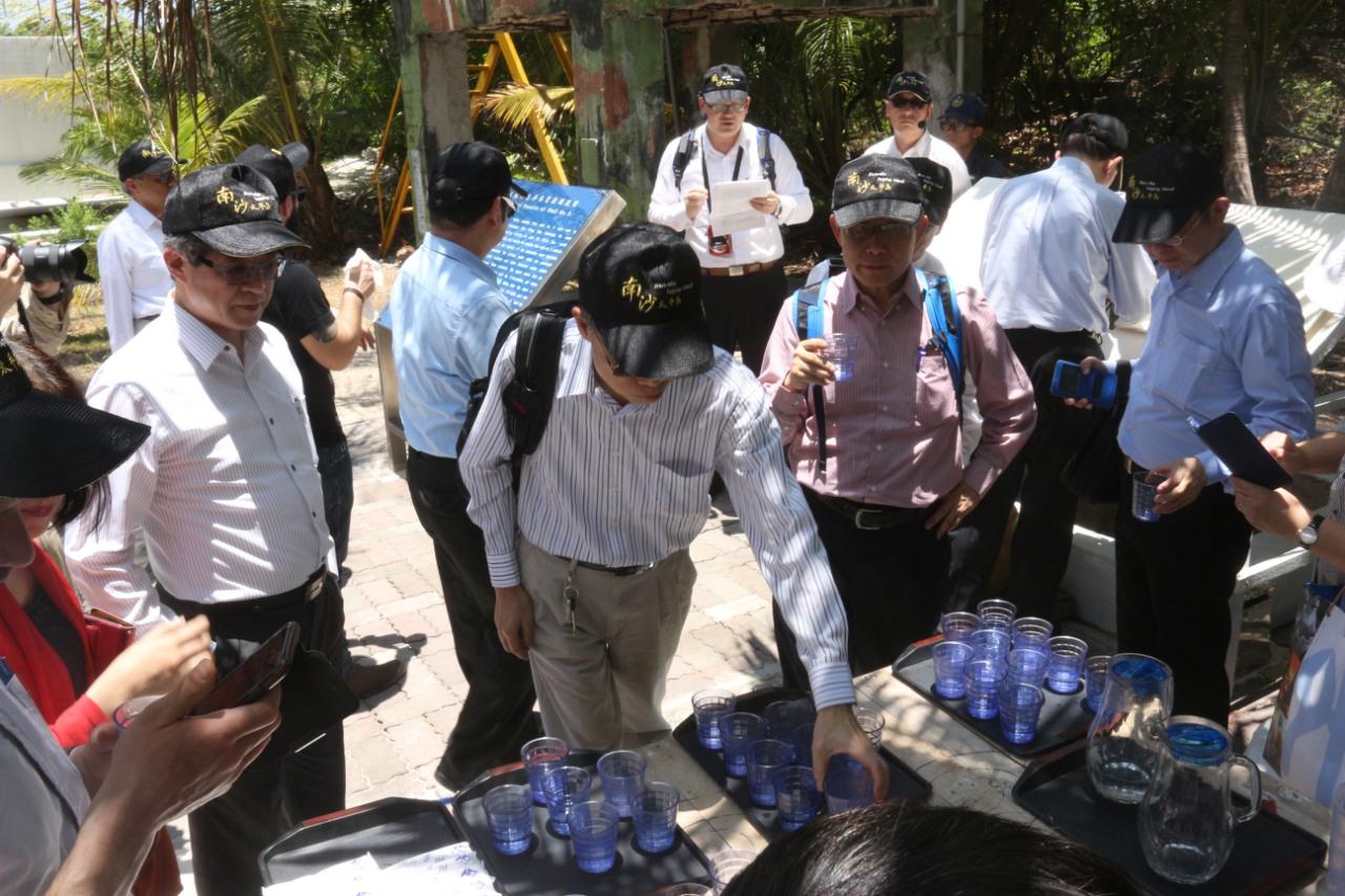 Visiting experts drink water from a well while listening to a briefing on water quality by Chang Ta-wei, head of the environmental division of the Agricultural Engineering Research Center.