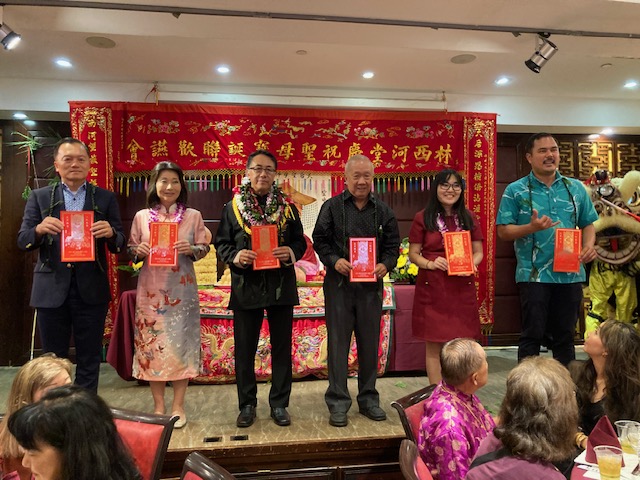 2024年5月19日林處長暉程(左一)於林西河堂慶祝聖母寶誕聯歡晚宴舞獅採青儀式與會長譚偉添(左三),夏威夷州副州長Sylvia Luke (左二), 夏威夷州眾議員Jenna Takenouchi(右二),檀香山市議員Calvin Say(右三),及檀香山市議員Tyler Dos Santos-Tam同向來賓祝賀龍年鴻運昌龍