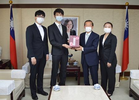 謝長廷・駐日代表（右２）からマスク、消毒ハンドジェル、柿渋消毒液、台湾インスタント麺、謝代表のメッセージなどが入った「愛心關懷袋」（まごころ福袋）を代表して受取る黄釋樟・東京大学台湾留学生会会長（左２）、日本大学４年生・陳俊男さん（左１）、立教大学４年生・李侑虔さん（右１）