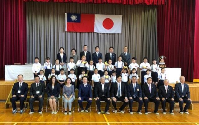 李処長（前列右5）と中尾代表（前列中央）、中川会長（前列右3）、村椿市長（前列右4）、野口校長（前列左1）、共田会長（前列左5）および児童らの集合写真