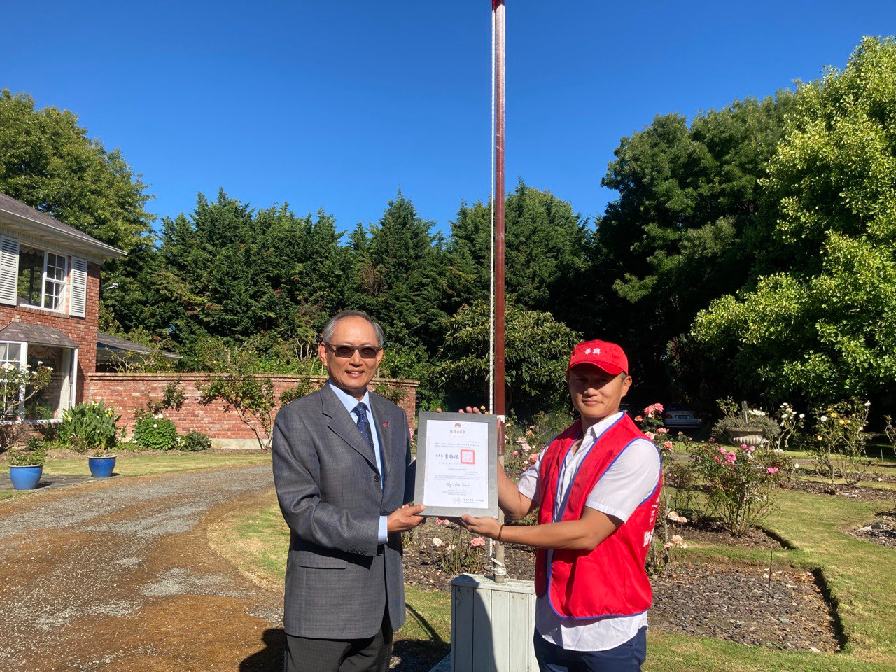 駐紐西蘭陳克明代表（左）轉致僑委會感謝狀予華興協會戴會長國鼎（右），感謝積極辦理110年國慶相關活動