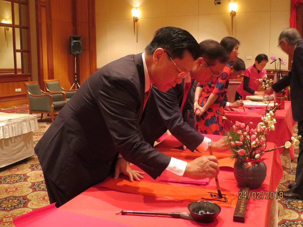 本處梁代表國新（左）與施僑務委員暨新加坡台北工商協會會長至隆(左2)及其他貴賓現場揮毫迎新春。