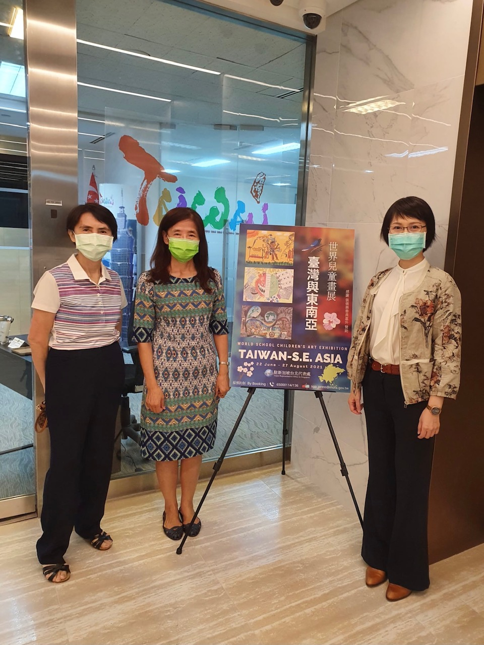 新加坡台北工商協會幹部(左)與世界兒童畫展海報合影