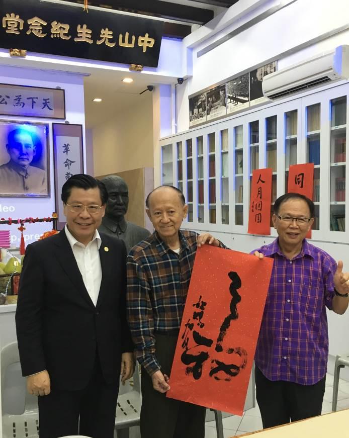 Representative Francis Liang (left) and Mr. Cham Seng Yin (right), President of the United Chinese Library, pose with Mr. Tan Khim Ser (center), President of the Life Art Society, as Mr. Tan holds up his calligraphic work. (2018/09/25)
