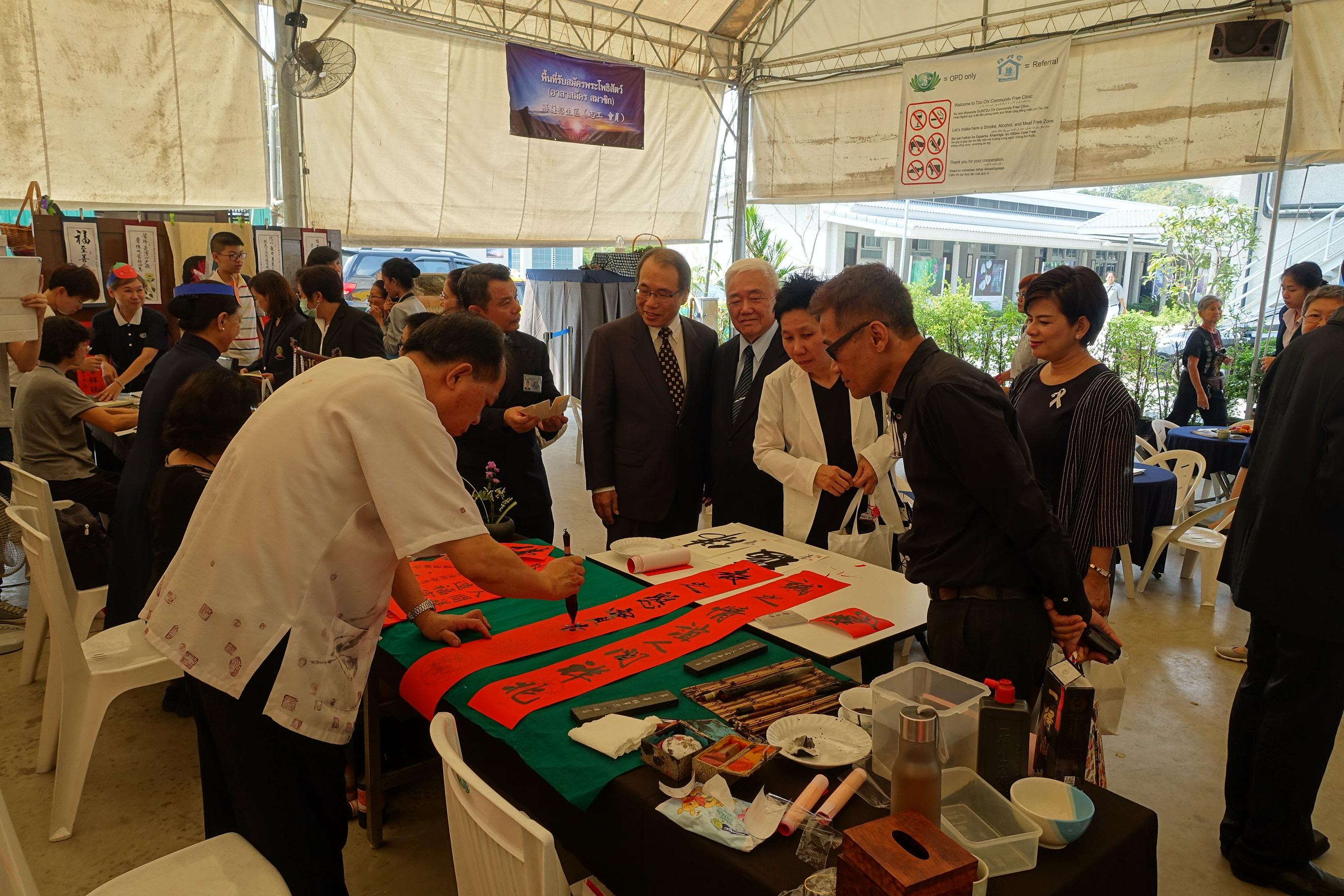 石柏士副代表(中)於感恩會結束後，偕黃僑務諮詢委員灌君(右)、陳僑務促進委員建良(左)欣賞書畫老師在現場揮毫。